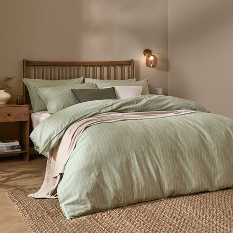 Linear Stripe Cotton Printed Duvet Cover Set in Forest green with fine white pinstripes, dressed on a bed with matching pillowcases in a wooden-framed bedroom setting.