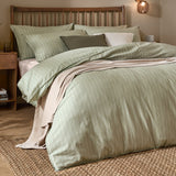 Linear Stripe Cotton Printed Duvet Cover Set in Forest, styled on a bed with matching pillowcases, dressed with cushions and a beige throw in a wooden-framed bedroom setting.