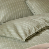 Close-up of the Linear Stripe Cotton Printed Duvet Cover Set in Forest, showing pillowcases and duvet in green cotton with fine white pinstripes.