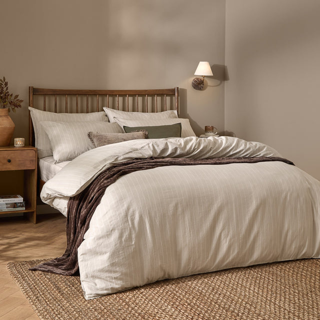 Linear Stripe Cotton Printed Duvet Cover Set in natural beige with matching pillowcases, dressed on a bed with a wooden slatted headboard in a bedroom setting.