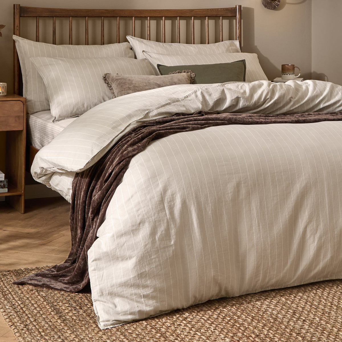 Linear Stripe Cotton Printed Duvet Cover Set in Natural, dressed on a bed with matching pillowcases and a brown throw, in a bedroom with a wooden slatted headboard.