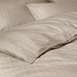 Close-up of the Linear Stripe Cotton Printed Duvet Cover Set in natural beige, showing pillowcases with fine off-white pinstripes and soft cotton folds.