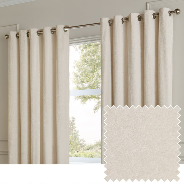 Ivory eyelet curtains in plain velvet fabric hanging on a brushed metal rod by a window, shown with a matching fabric swatch.