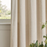 Ivory Lustre Velvet eyelet curtains shown in soft folds by a window, fully lined fabric with a subtle sheen and even drape.