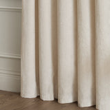 Lustre Velvet eyelet curtains in ivory, close-up of soft pile fabric falling in deep folds, fully lined against a neutral wall and wood floor.