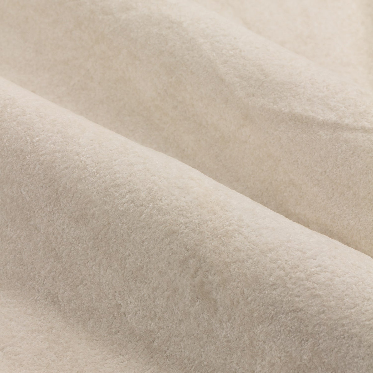Close-up of Lustre Velvet Plain Fully Lined Eyelet Curtains in ivory, showing the soft velvet pile and folded polyester fabric catching the light.