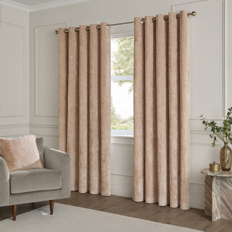 Lustre Velvet Plain Fully Lined Eyelet Curtains in oyster, shown floor-length either side of a window on a metal pole, styled in a neutral living room with an armchair and marble side table.