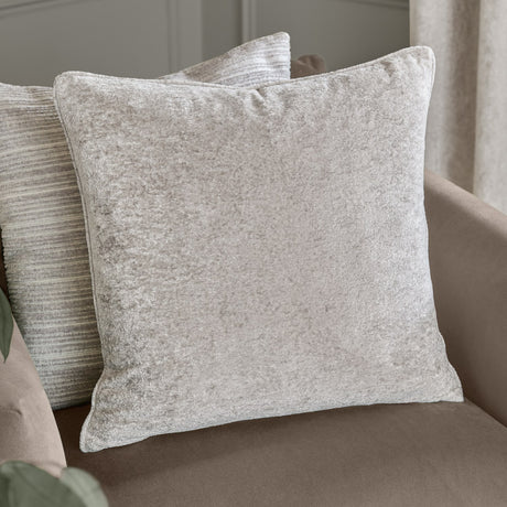 Lustre Velvet Plain Polyester Cushion in silver with a crushed-velvet sheen, square shape and piped edge, styled on a sofa with a striped cushion behind.