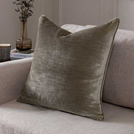 Luxe Velvet Plain Polyester Cushion in mink, a square scatter cushion with piped edges shown on a neutral sofa beside a vase and books.