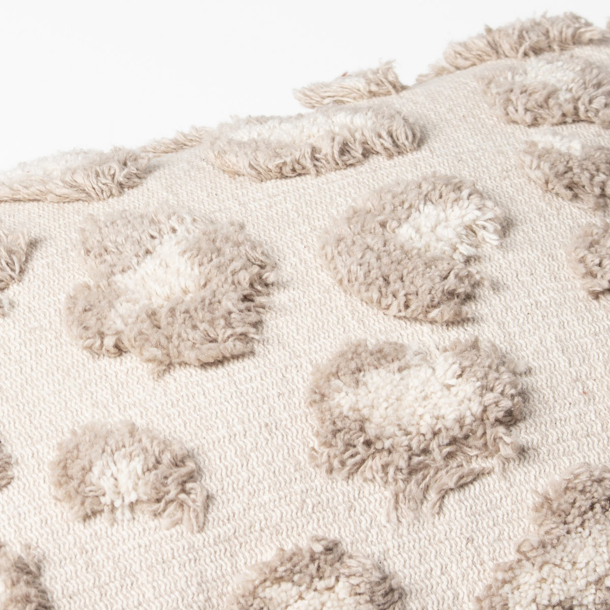 Close-up of the Maeve Animal Cotton Cushion in natural, showing raised tufted leopard-print spots in beige and white on a woven cotton base.