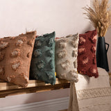 Maeve Animal Cotton Cushion in natural, styled with coordinating tufted leopard-print cushions in terracotta, teal, beige and burgundy on a wooden bench with a woven throw.