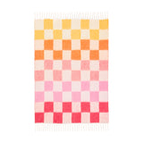 Maisie Check Polyester Throw in Citrus Blush, a woven checkerboard blanket fading from yellow and orange to pink and coral on a cream ground, with fringed edges on a white background.