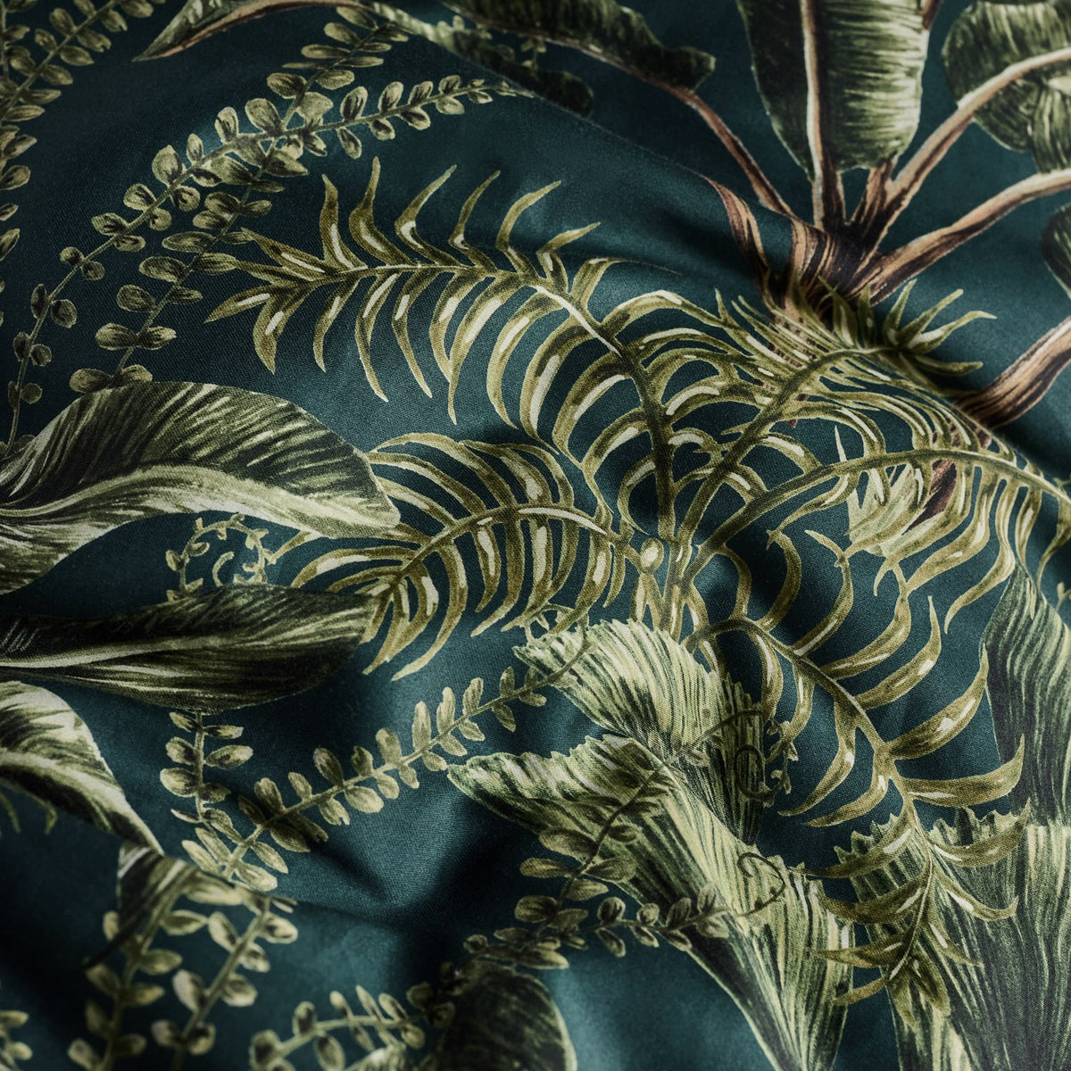 Majorelle Cotton Leaf Duvet Cover Set in green, close-up of tropical palm frond and fern print cotton fabric in deep green tones.