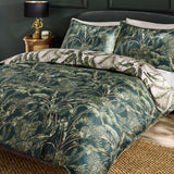 Majorelle Cotton Leaf Duvet Cover Set in green, styled on a bed with matching pillowcases featuring a tropical palm and fern print, shown in a dark bedroom setting.