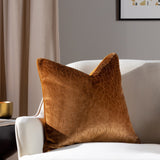 Malans Geometric Velvet Cushion in bronze, a 45 x 45cm square cushion with a crackled cut-velvet pattern, shown on a cream armchair in a living room setting.