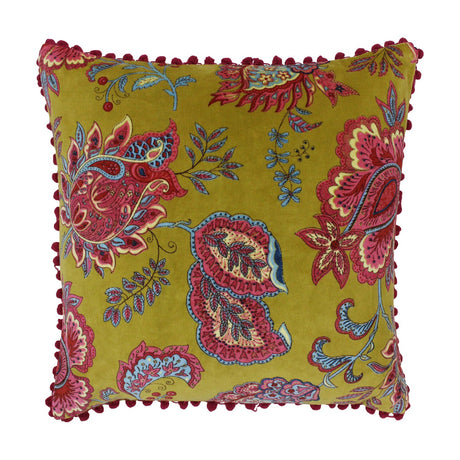 Malisa Velvet Cotton Cushion in Lemon Curry, a square mustard-yellow cover with pink, red and blue paisley floral print and red pom-pom trim, shown on a white background.