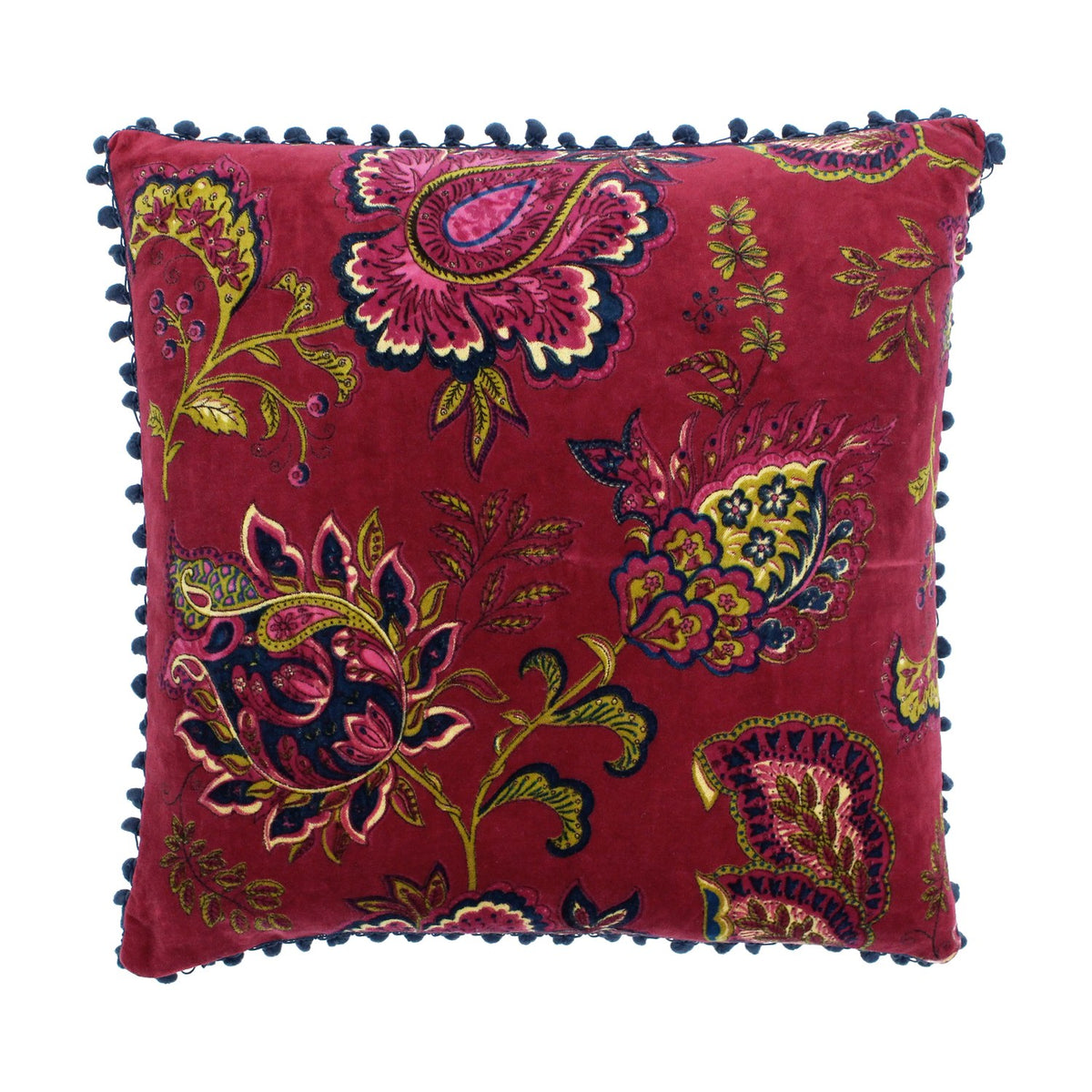 Malisa Velvet Cotton Cushion in Pomegranate, a square red cushion with paisley and floral print in pink, gold-green and blue, edged with blue pompom trim on a white background.