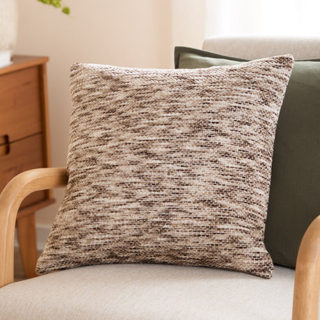 Malvern Jacquard Chenille Cushion in Cedar, a 45x45cm square cushion with a mottled brown, stone and cream woven texture, shown on a wooden armchair beside a green cushion.
