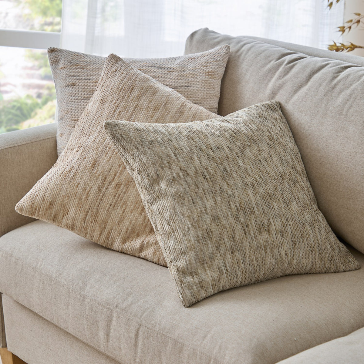 Malvern Jacquard Chenille Cushions in natural sandy tones with subtle horizontal weave texture, styled together on a beige sofa near a window.