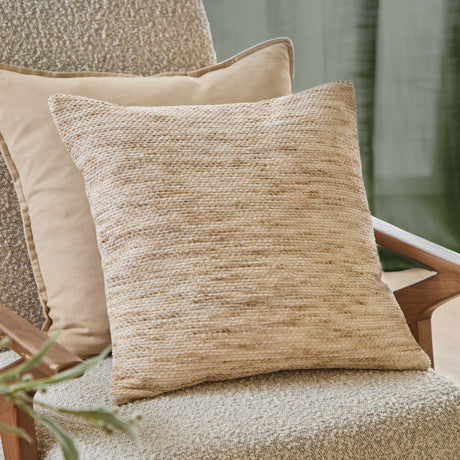 Malvern Jacquard Chenille Cushion in oatmeal, a square 45x45cm cushion with a mottled, flecked chenille weave, shown on a woven armchair with a beige piped cushion behind.