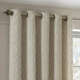 Manhattan Velvet Fully Lined Eyelet Curtains in ivory, shown on a brushed metal pole with eyelet header, textured geometric weave visible on the fabric drop.