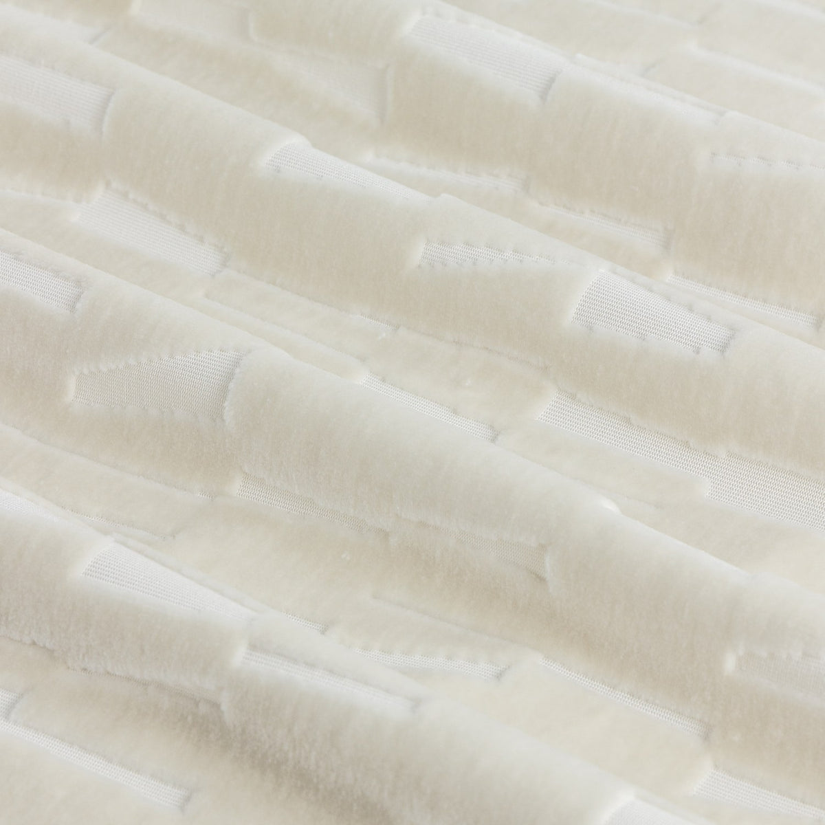 Close-up of the Manhattan ivory eyelet curtain fabric, showing cut velvet with a textured geometric block pattern raised against a smooth polyester ground.