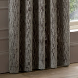Manhattan Velvet Fully Lined Eyelet Curtains in mink, shown floor-length with eyelet header folds beside a window, textured geometric velvet pattern in earthy brown tones.