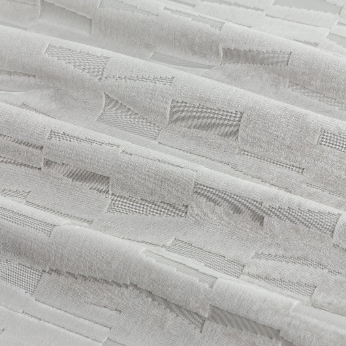 Close-up of Manhattan silver-grey cut velvet eyelet curtain fabric, showing a raised geometric block pattern with a soft pile finish.