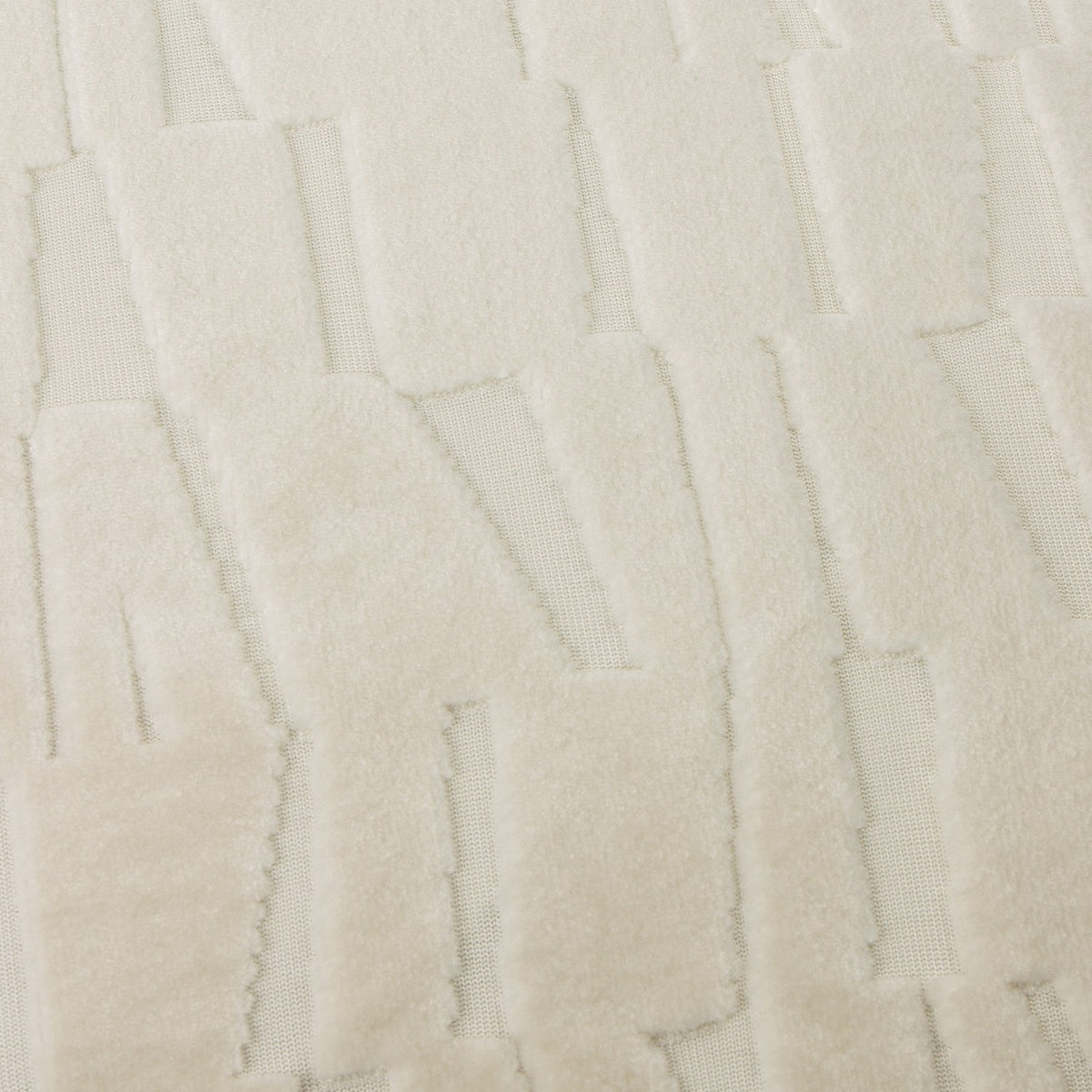 Close-up of the Manhattan Geometric Velvet Cushion in ivory, showing cut-velvet pile with angled blocks forming an irregular brickwork pattern.
