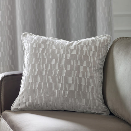 Manhattan Geometric Velvet Cushion in silver with cut velvet geometric pattern, shown on a grey sofa in a living room setting.