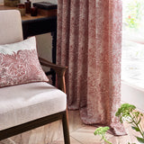 Marigold Jacquard pencil pleat curtains in russet foliage pattern, shown pooling on a wooden floor beside a matching cushion and armchair in a living room setting.