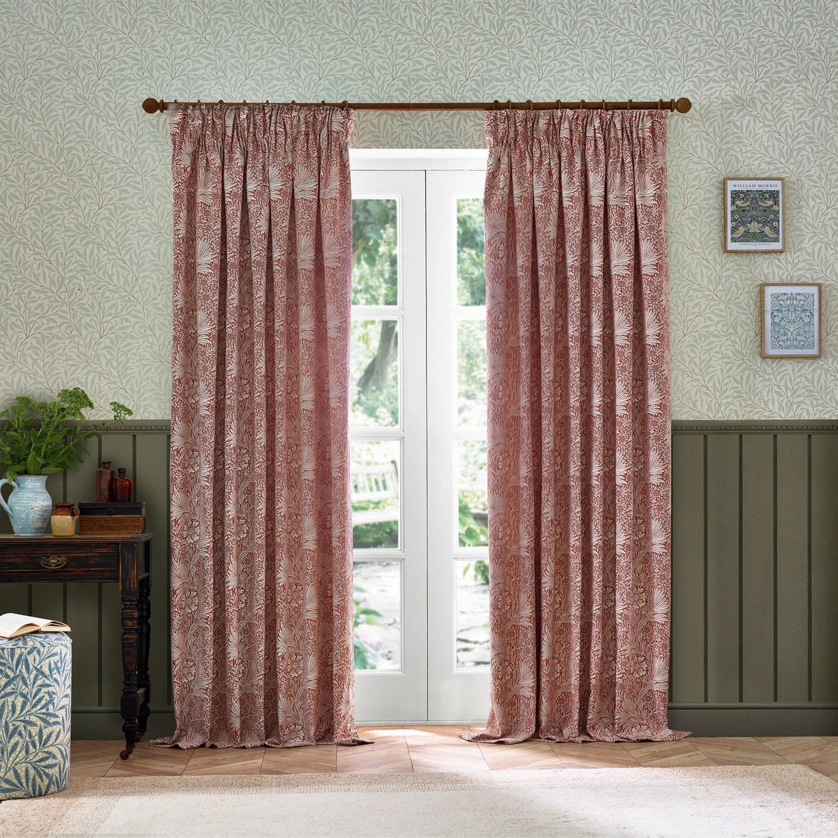 Marigold Jacquard pencil pleat curtains in russet, hung either side of glazed doors in a living room with sage green wainscoting and floral wallpaper.