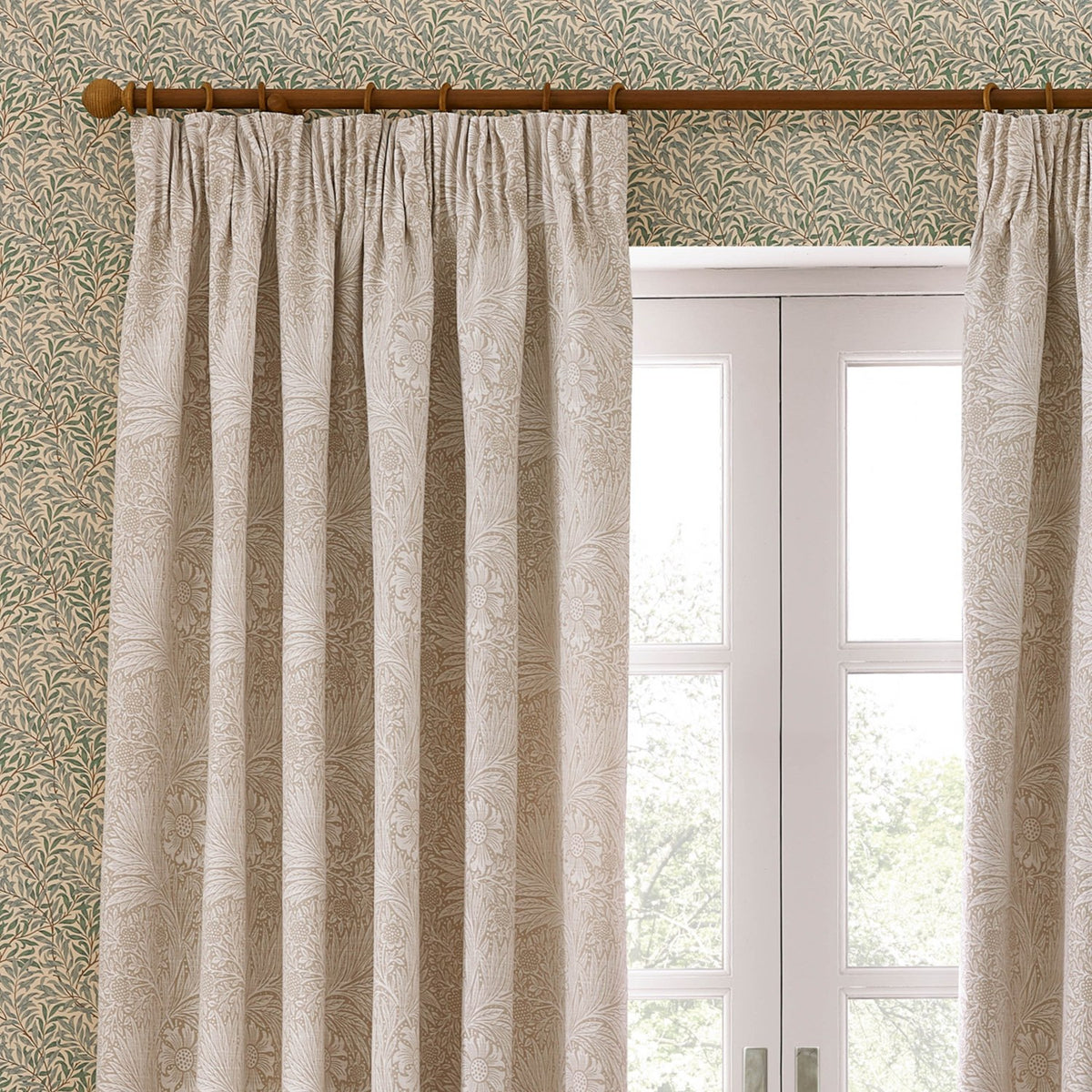 Marigold Jacquard pencil pleat curtains in stone, woven with a raised floral and foliage pattern, shown pleated on a wooden pole beside a white French door.