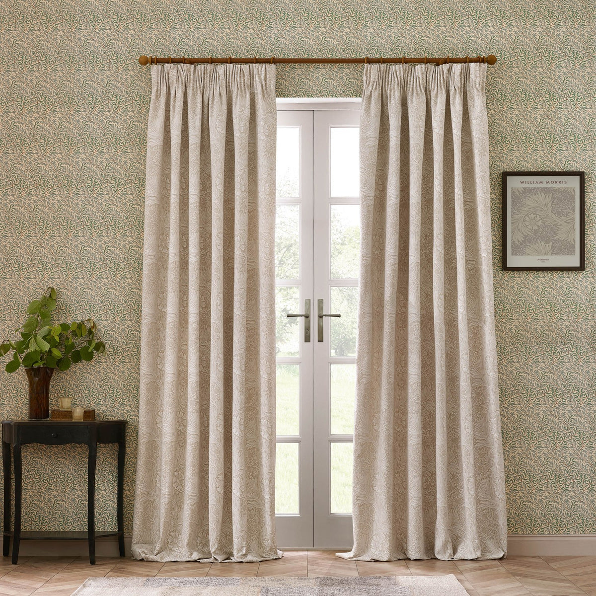 Marigold Jacquard pencil pleat curtains in stone, hung on a wooden pole beside French doors, showing the woven floral pattern in a living room setting.