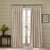 Marigold Jacquard pencil pleat curtains in stone, hung on a wooden pole beside French doors, showing the woven floral pattern in a living room setting.