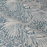 Close-up of Marigold Jacquard pencil pleat curtain fabric in indigo blue, showing swirling foliage and sunburst marigold patterns on a soft cream polyester ground.