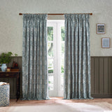 Marigold Jacquard pencil pleat curtains in indigo blue floral pattern on cream ground, shown pleated at a French door in a living room with patterned wallpaper.
