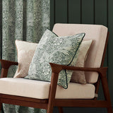 Marigold Jacquard Velvet Cushion in leaf green with woven floral pattern and dark piped edge, styled on a pink armchair beside a matching curtain.