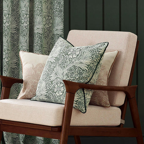 Marigold Jacquard Velvet Cushion in leaf green with woven floral pattern and dark piped edge, styled on a pink armchair beside a matching curtain.