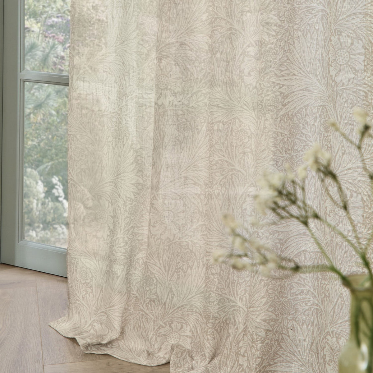 Marigold Damask Linen Curtain Panel in cream, showing a trailing floral damask print, draped by a window with pooled fabric on a wooden floor.