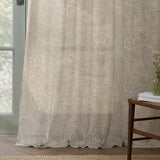 Marigold Damask Linen Curtain Panel in cream, showing a Morris foliage and flower print in putty tone, hung by a glass door beside a wooden side table.