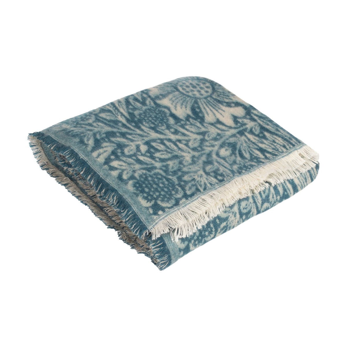 Marigold Jacquard Cotton Throw in indigo, folded showing a woven botanical floral pattern in teal and cream with white fringed edges, on a plain white background.