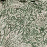 Close-up of the Marigold Jacquard Cotton Throw in Leaf Green, cotton fabric with a woven floral pattern in green and cream, shown draped in folds.
