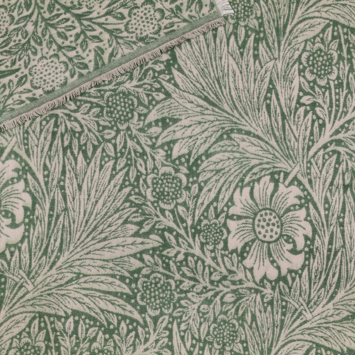Marigold Jacquard Cotton Throw in Leaf Green, folded to show reversible woven pattern with green florals on cream and cream motifs on green, fringed edge visible.