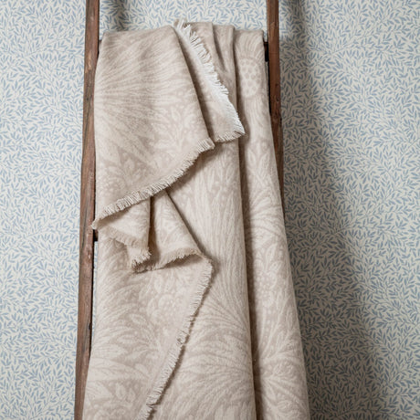 Marigold Jacquard Cotton Throw in stone, draped over a wooden ladder, showing a fringed edge and tonal woven leaf and floral pattern.