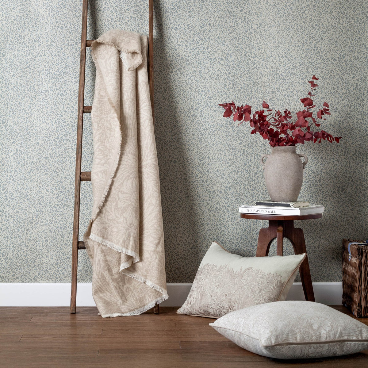 Marigold Jacquard Cotton Throw in stone, draped over a wooden ladder, showing a fringed edge and tonal floral jacquard pattern in a living room setting.