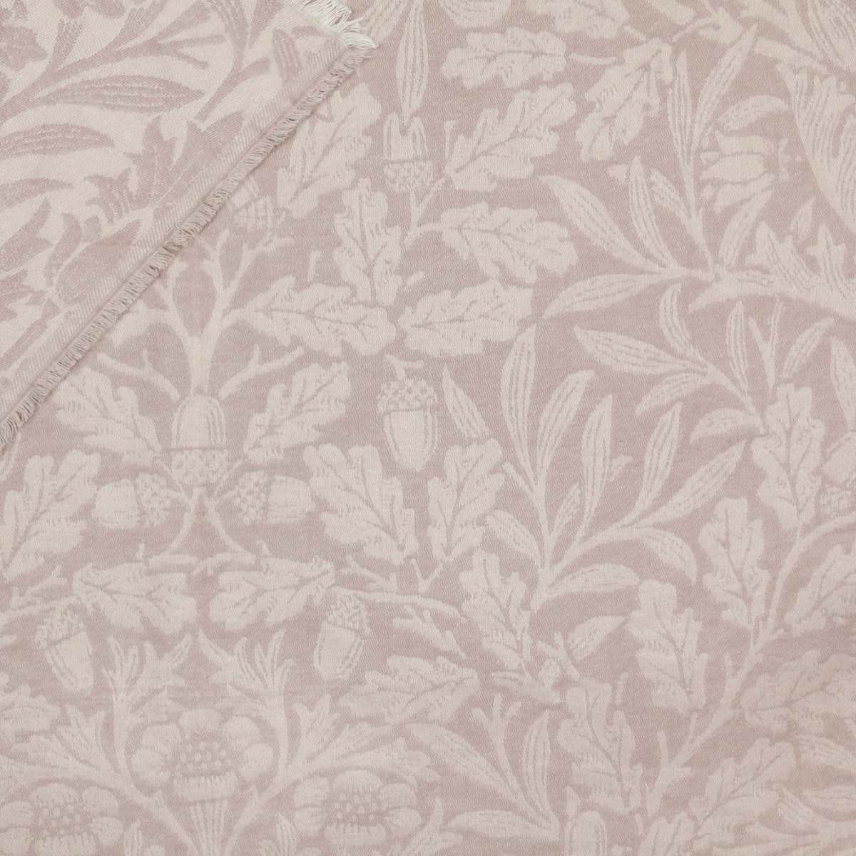 Marigold Jacquard Cotton Throw in Stone, close-up of woven leaf, acorn and floral pattern in tonal beige with a fringed edge visible.