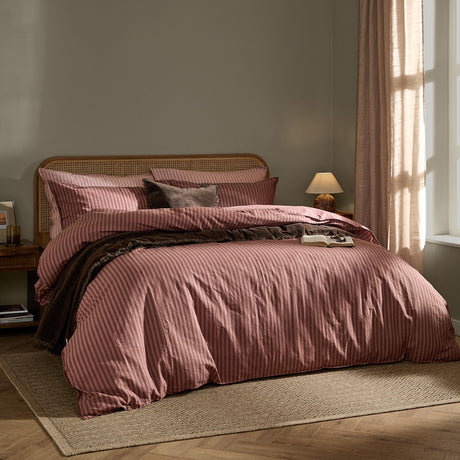 Marlow Stripe Cotton Printed Duvet Cover Set in rosewood pink and chocolate brown, styled on a bed with matching pillowcases and a brown velvet cushion in a bedroom setting.