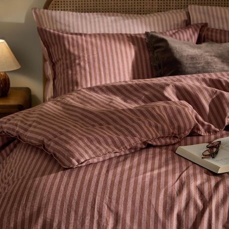 Marlow Stripe Cotton Duvet Cover Set in chocolate/rosewood pink stripe, shown styled on a bed with matching pillowcases and a grey cushion in a bedroom setting.