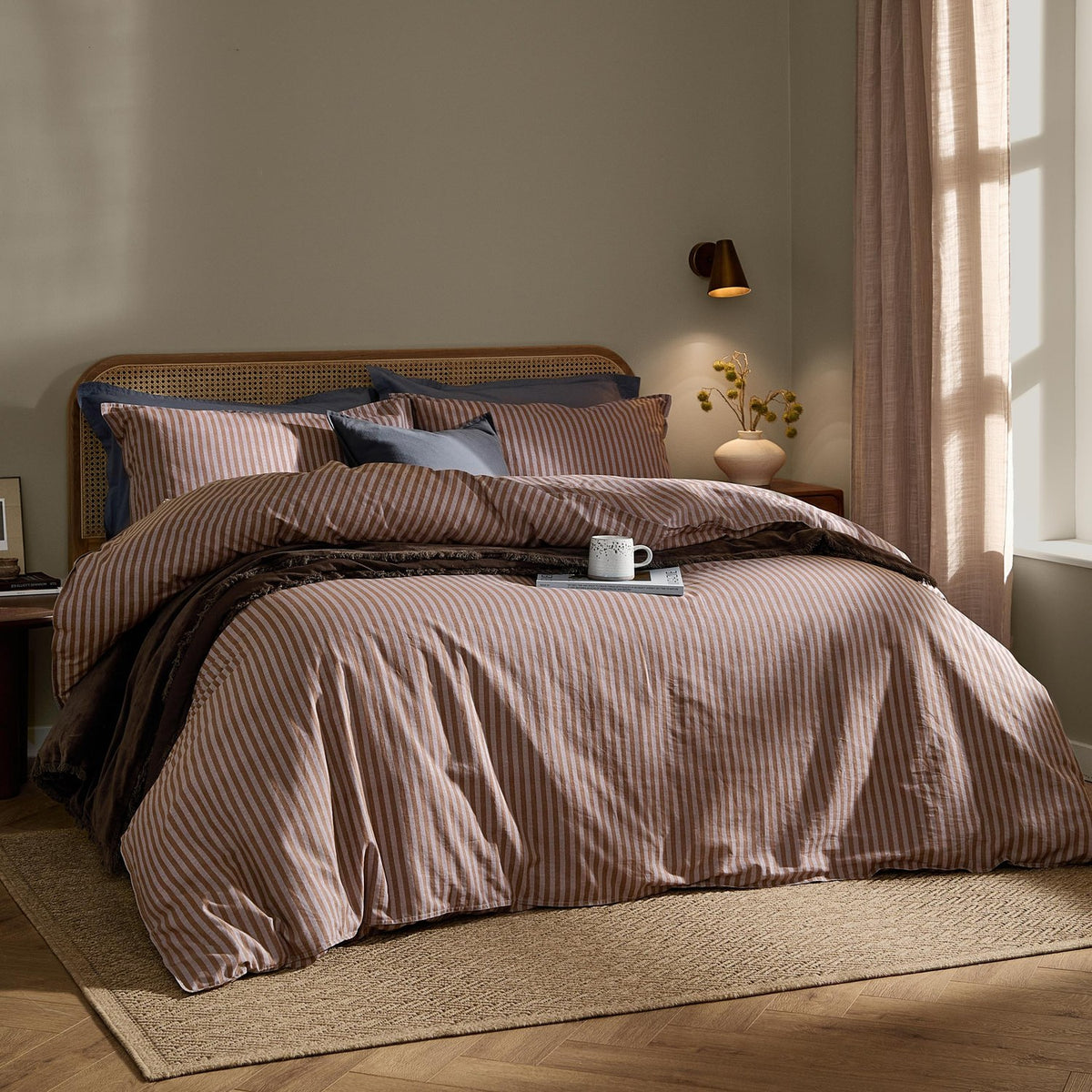 Marlow Stripe Cotton Printed Duvet Cover Set in cocoa/vintage blue on a bed with rattan headboard, styled with navy pillowcases in a bedroom setting.